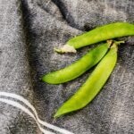 Close-up van verse, heldergroene sugar snaps op een donkere doek