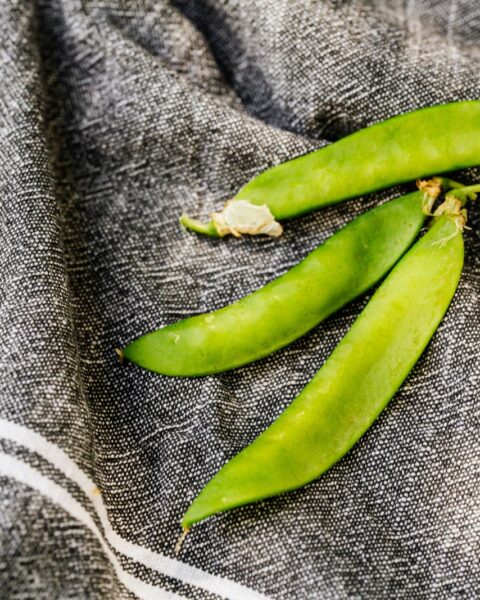 Close-up van verse, heldergroene sugar snaps op een donkere doek