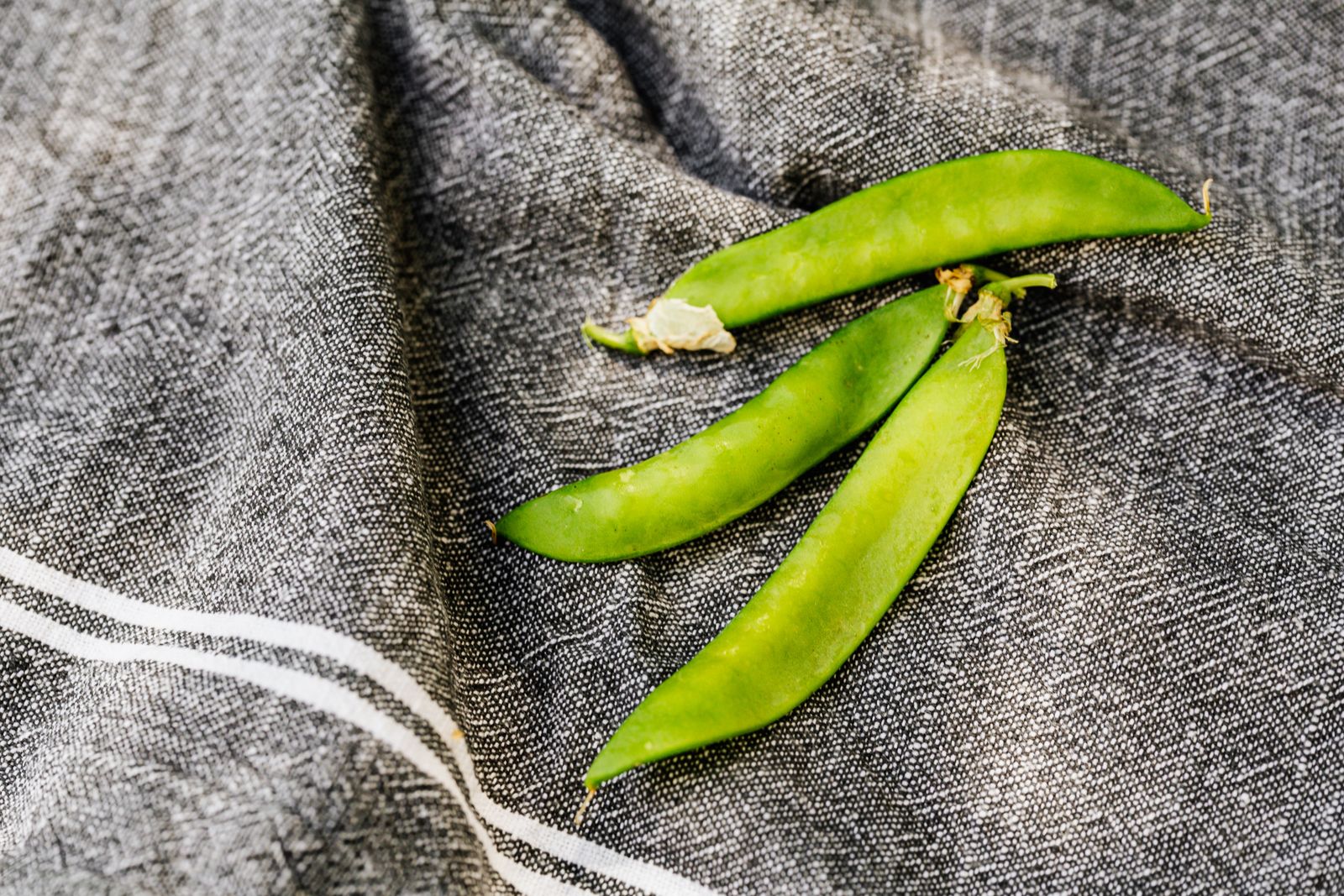 Close-up van verse, heldergroene sugar snaps op een donkere doek